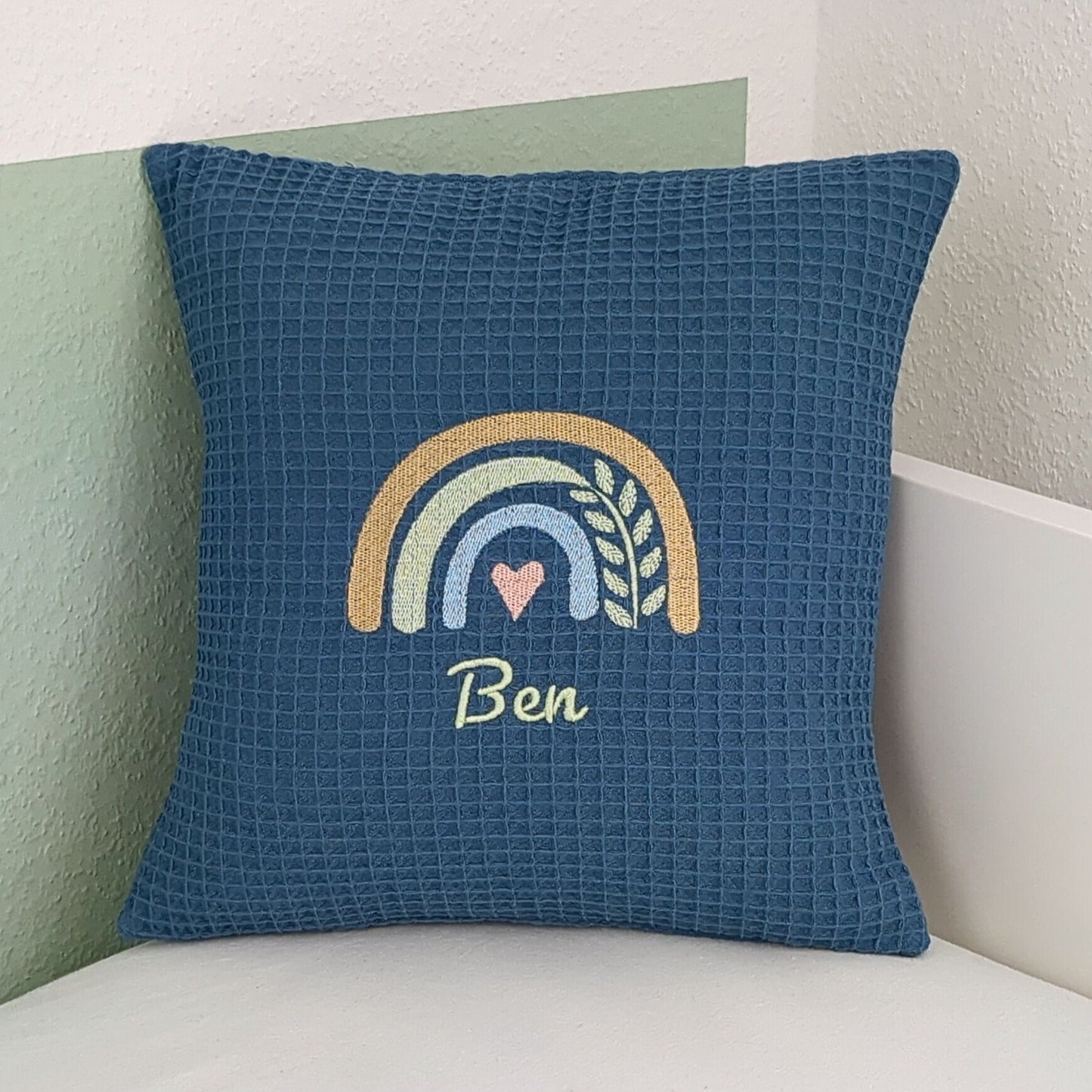 Kissen aus Baumwollstoff in blau, bestickt mit Regebogen und Name.