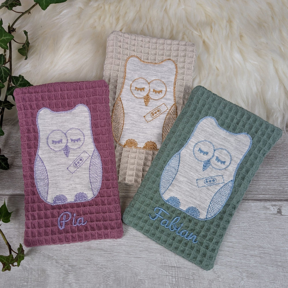 Stoffhülle aus Baumwolle für Kühlakku in creme türkis und lavendel, bestickt mit Eule und Name.