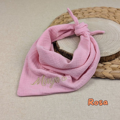 Es ist ein Halstuch aus Musselin bestickt mit  Name und einem kleinen Herzen hinter dem Namen zu sehen. Das Tuch hat die Farbe Rosa.