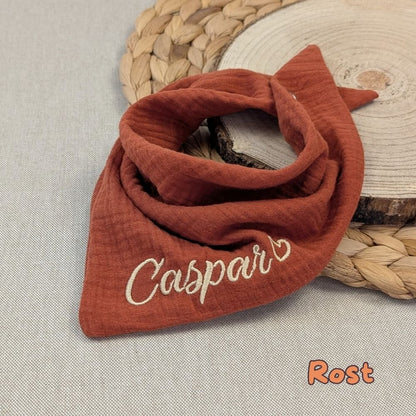 Es ist ein Halstuch aus Musselin bestickt mit  Name und einem kleinen Herzen hinter dem Namen zu sehen. Das Tuch hat die Farbe Rost.