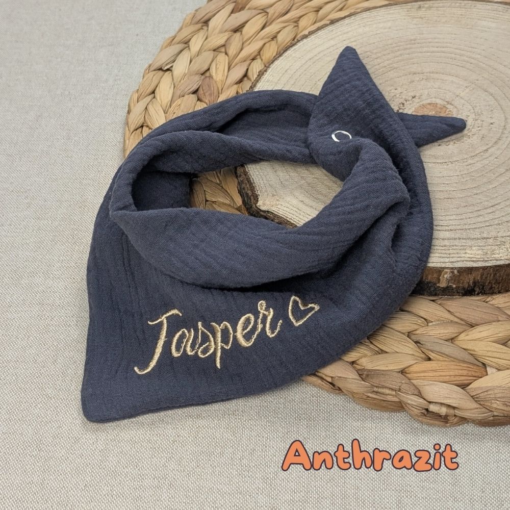 Es ist ein Halstuch aus Musselin bestickt mit dem Namen Jasper und einem kleinen Herzen hinter dem Namen zu sehen. Das Tuch hat die Farbe anthrazit.