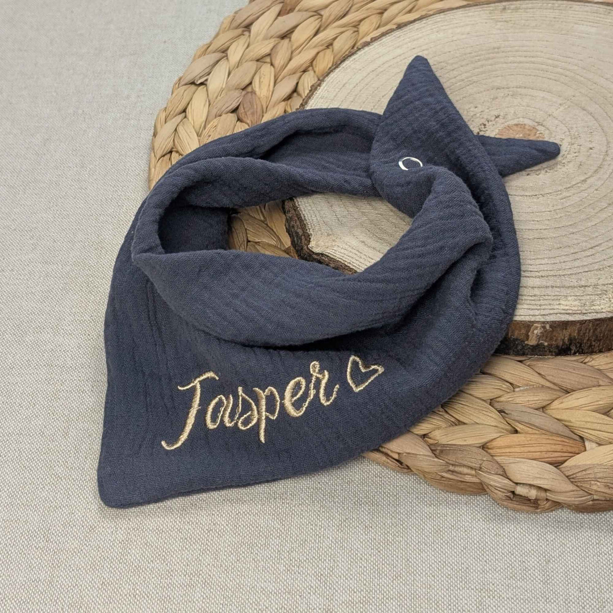 Es ist ein Halstuch aus Musselin bestickt mit dem Namen Jasper und einem kleinen Herzen hinter dem Namen zu sehen. Das Tuch hat die Farbe anthrazit.