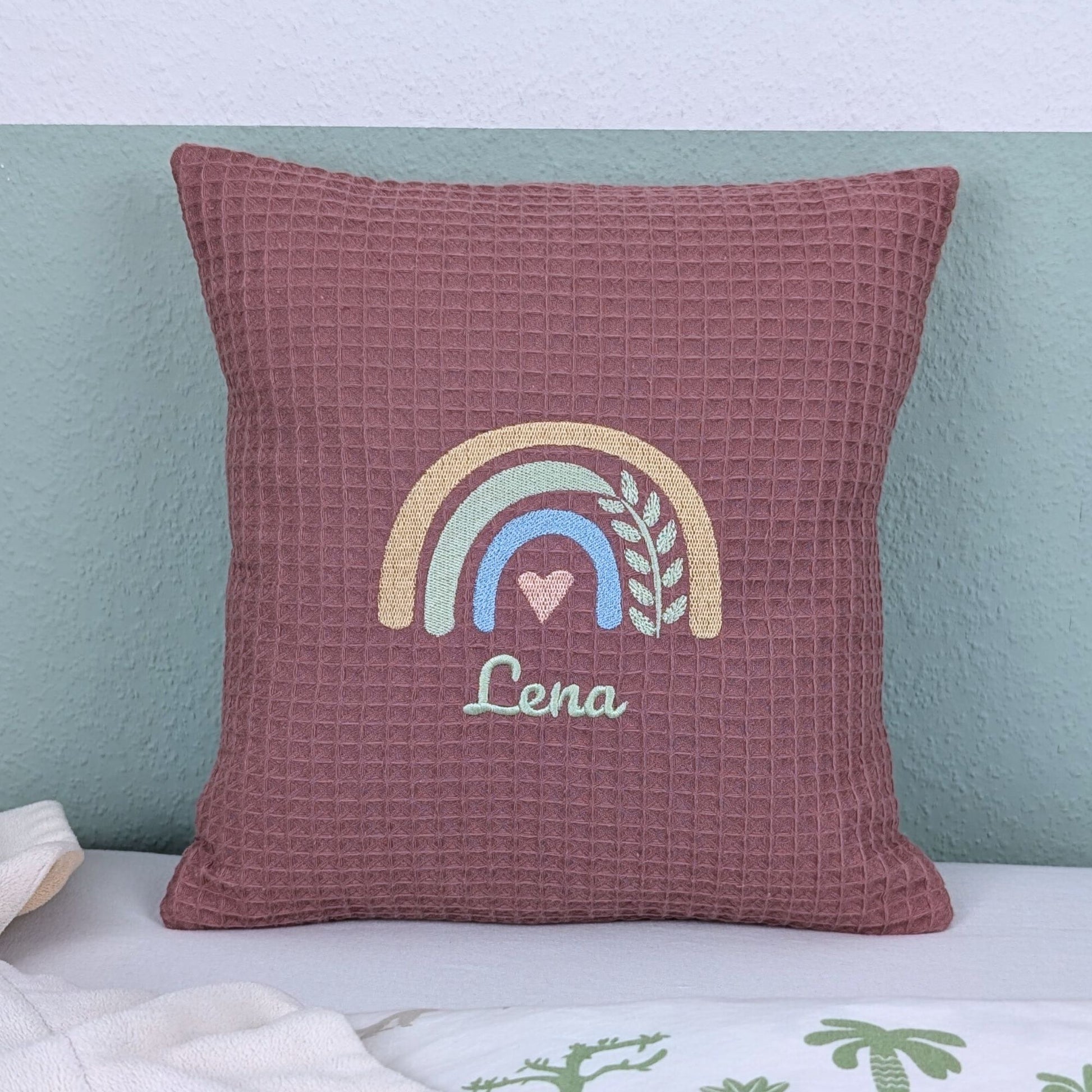 Kissen in der Größe 30 x 30 cm, aus Waffelstoff in der Farbe altrosa, bestickt mit einem Regenbogen und darunter steht mittig eine Name.